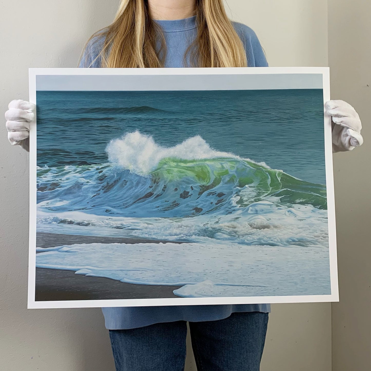 an artist holding a limited edition print of an ocean wave oil painting